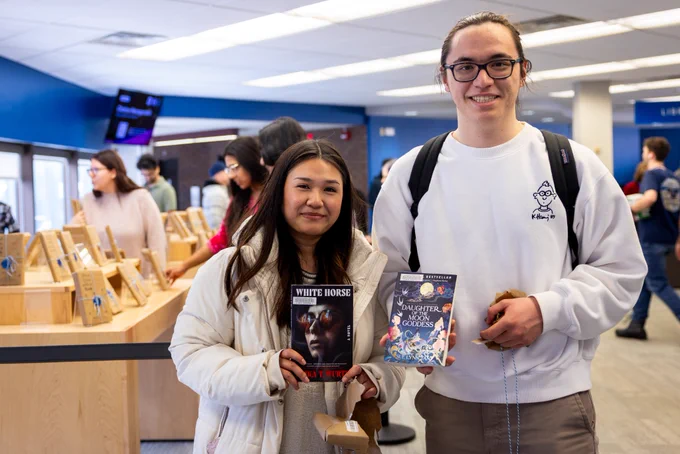 Students show off their surprise book selections after unwrapping