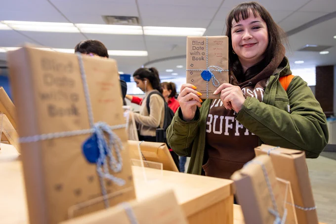 Student poses with their Blind Date with a Book pick after unwrapping