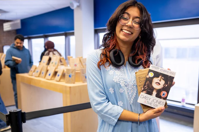 Student poses with their Blind Date with a Book pick after unwrapping