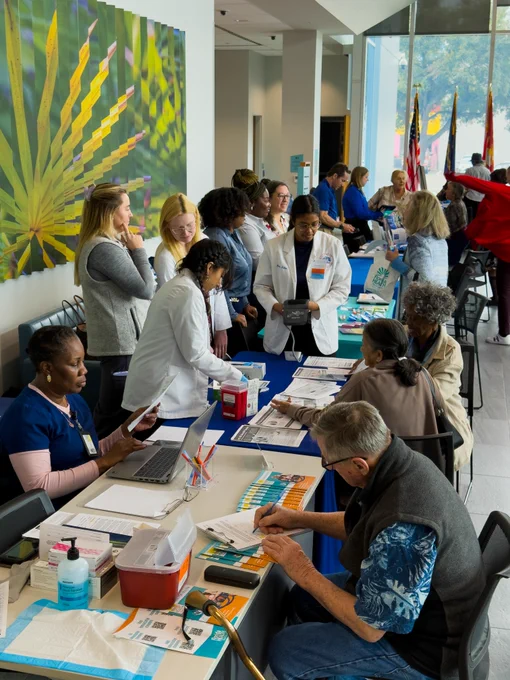 Agency professionals and seniors are interacting at an outreach event with informational tables and supplies.
