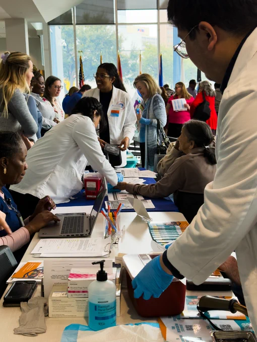 Agency professionals and seniors are interacting at an outreach event with informational tables and supplies.