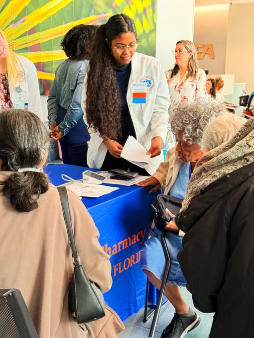 Agency professionals and seniors are interacting at an outreach event with informational tables and supplies.