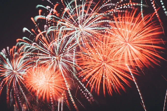 six fireworks against a dark sky. The top three fire works are red and blue; the bottom three are red.