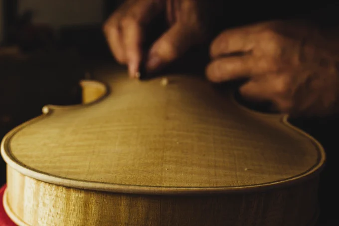 Close up of hands working on the body of a violin