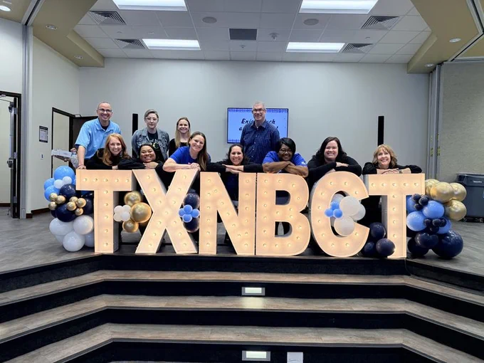 Teach Plus Fellows and Alumni along with Policy Program Manager, Dr. Hjamil Martínez-Vázquez, pose with the TXNBCT marquee letters and blue, white, and gold balloons.
