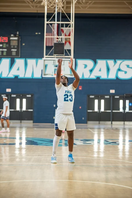 Basketball player wearing jersey number 23 takes a jump shot on an indoor court with 'MANTA RAYS' visible on the wall behind.