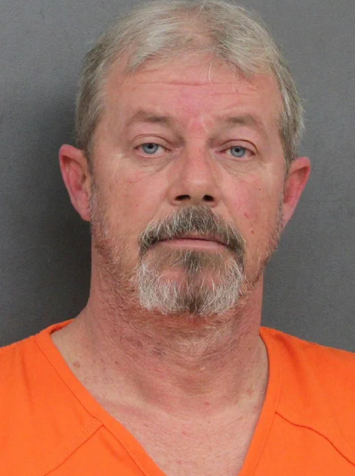 Mugshot of person wearing orange with a grey background.