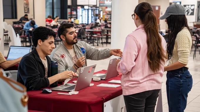 Two TAMIU employees help two students with financial aid questions.