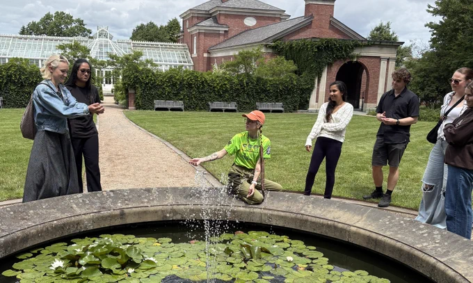 A photo taken during one of Suchinta Arif's community-engaged workshops in 2025. It shows a group of people standing around a fountain as someone explains something to them.