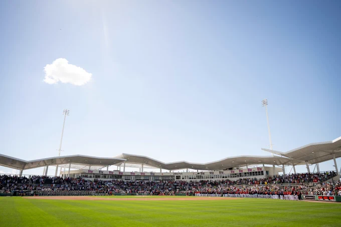 A wide shot of JetBlue Park taken from center field with the Red Sox and Northeastern teams standing on the lines for the National Anthem during pregame ceremonies.