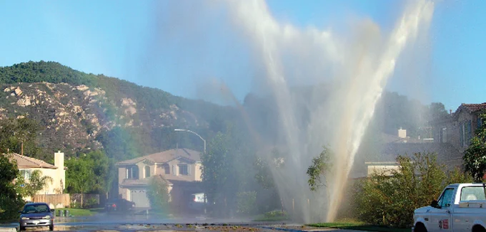 Water gushes out of main line and into residential street.
