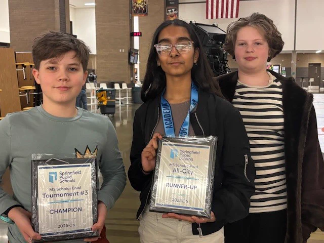 Three students holding two plaques with one wearing a medal