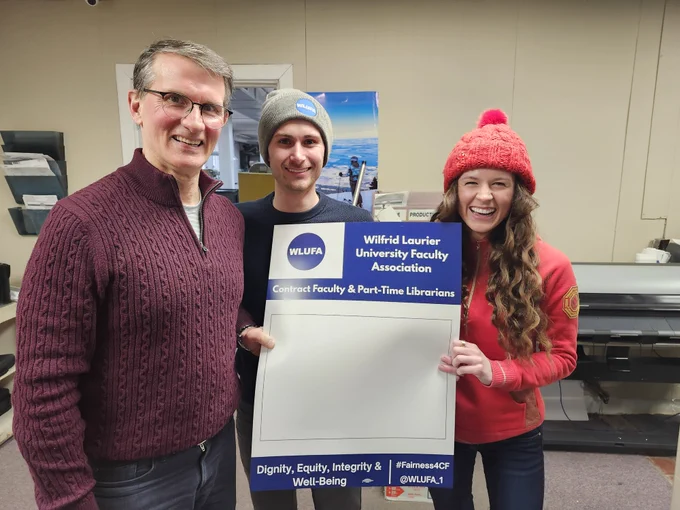 Three unionized workers at a local print shop hoping up the new WLUFA picket signs.