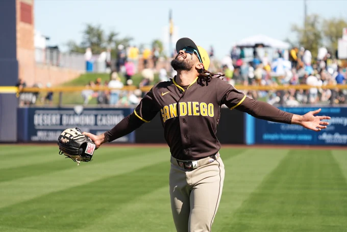 Fernando Tatis Jr. looks up to the sky and smiles because baseball is back. He wears a brown San Diego Padres uniform with yellow lettering.
(Photo: Zach Gardner, Major League Baseball)