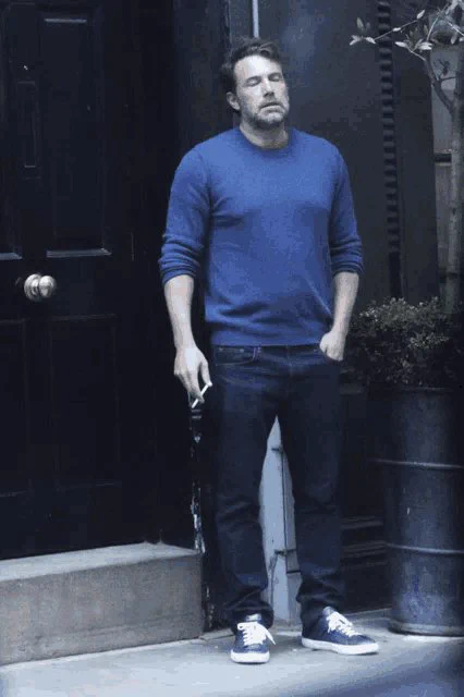 Man in blue shirt smokes because he is so stressed out about a random hockey game on a Sunday morning in February.