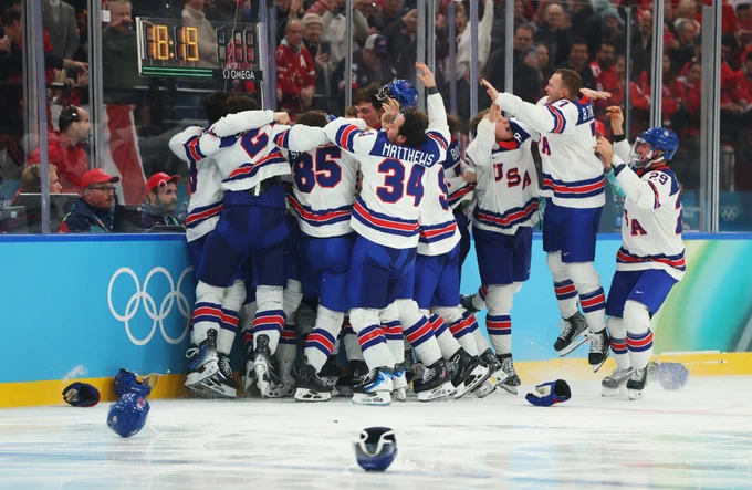 Team USA on ice in USA uniforms celebrating their gold medal victory.