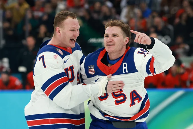 Brady and Matthew Tkachuk on ice in USA uniforms celebrating their gold medal.