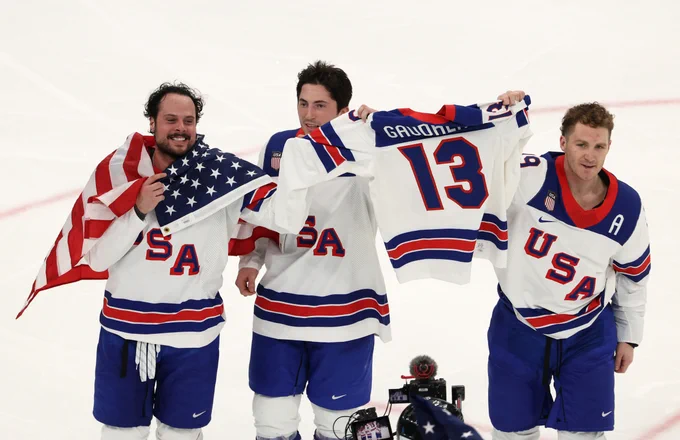 Auston Matthews, Zach Werenski and Matthew Tkachuk on ice in USA uniforms skating around with a Johnny Gaudreau USA jersey.