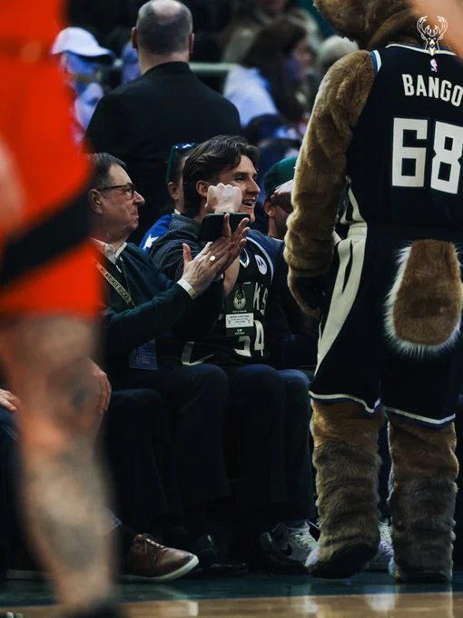 A photo of Badgers QB Colton Joseph sitting courtside at Fiserv Forum.