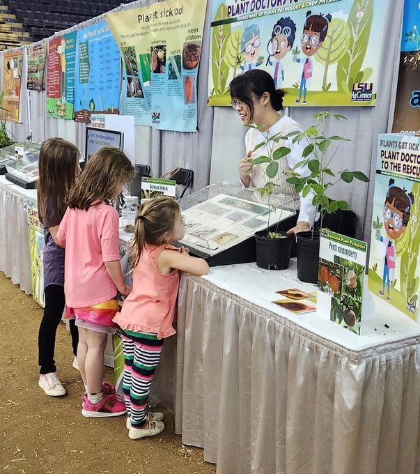 children looking at a display with a woman behind a table
