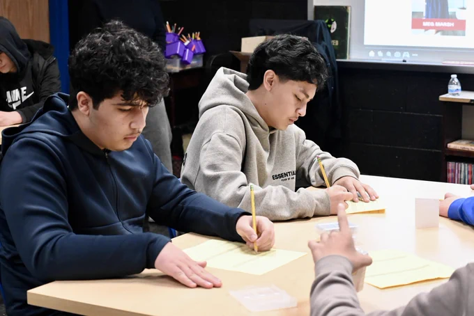 Students take notes during a career day presentation