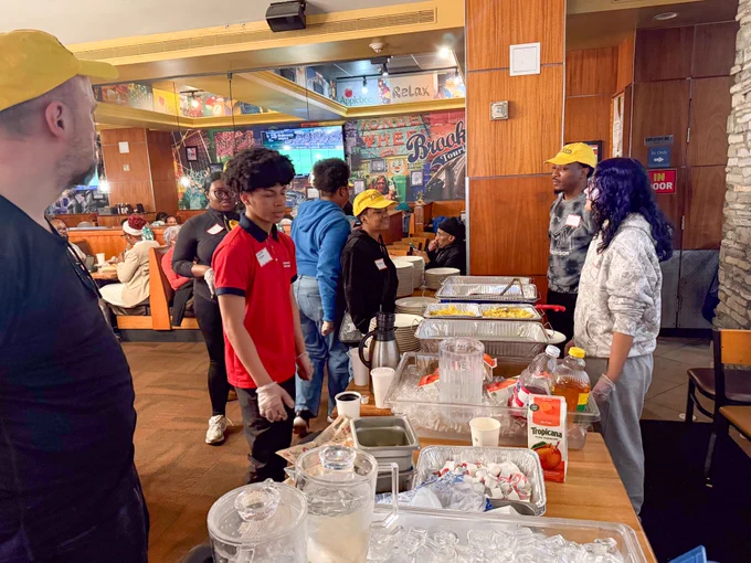 Event goers stand in line to receive breakfast plates. 