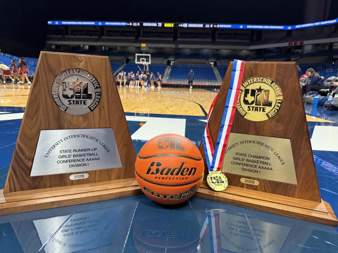 The first and second place UIL trophy on the court with a basketball between them.