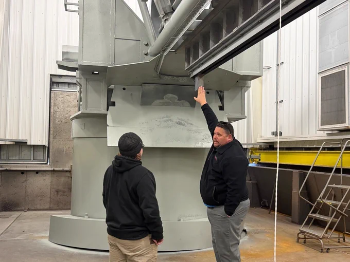 A NASA Wallops employee gestures to a piece of technology while a student looks on