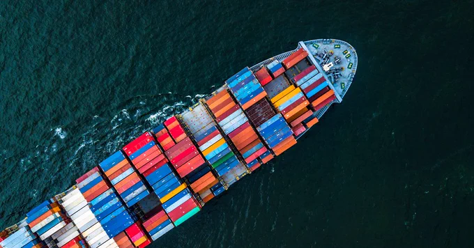 Aerial view of a large cargo ship carrying colorful containers on the ocean.