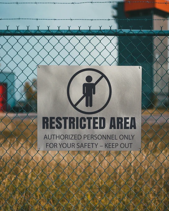 Custom Titanium Sign Laser Fused With Restricted Area Icon And Message Mounted Onto A Fence Outdoors In Field Near Compound