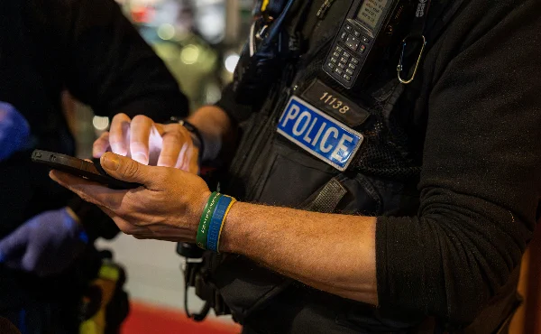 Photo of a police officer typing into a mobile phone.