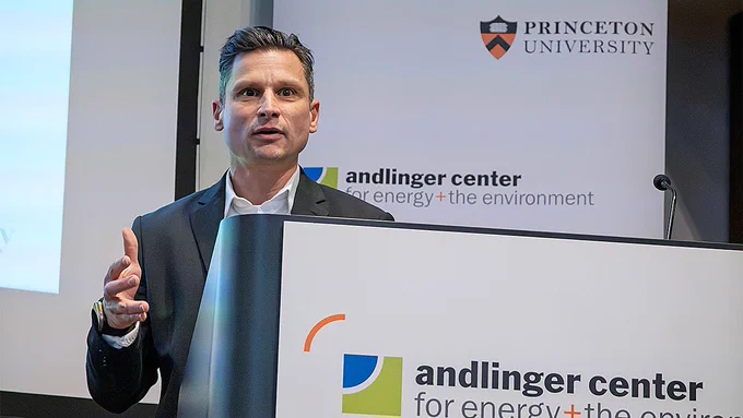 A man in a suit speaks at a podium with "Andlinger Center for Energy and the Environment" logo.