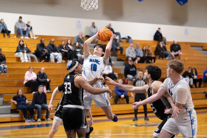 MSMC Men's Basketball player jumping to make a basket. 