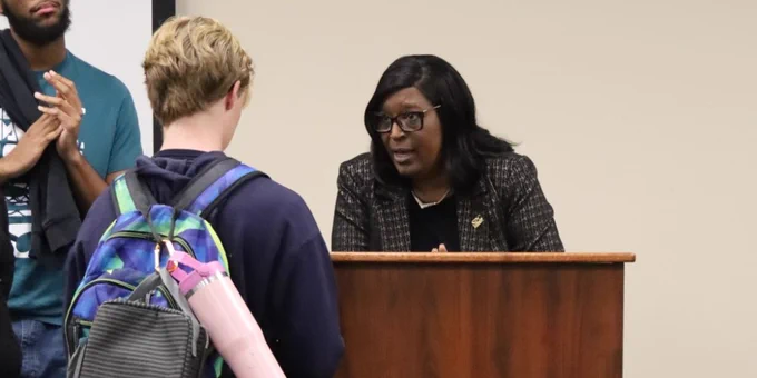 Dr. Williams speaking to a student while at a podium. A student stands in the background.