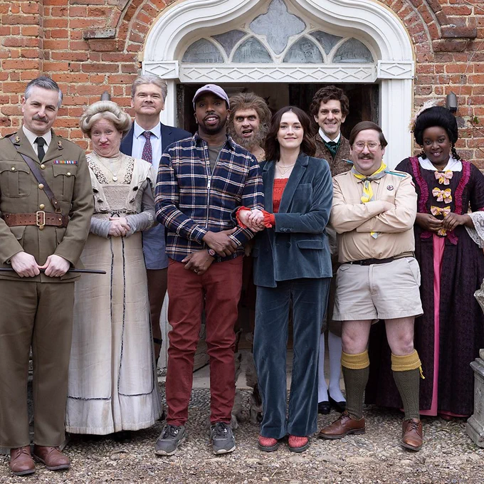 The cast of Ghosts stand in the doorway of Button House. 