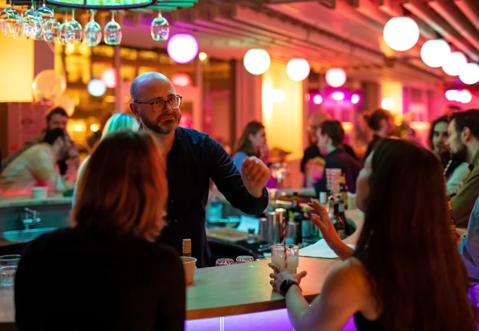 A man standing inside a round bar helping a women who wants a drink