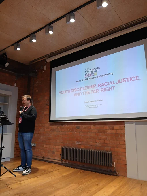 Martin stood in front of the screen. The slide says youth discipleship, racial justice, and the far-right 
