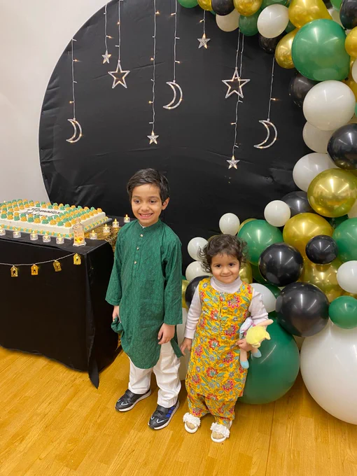 Two young pupils with green, gold, white, and black balloons.

