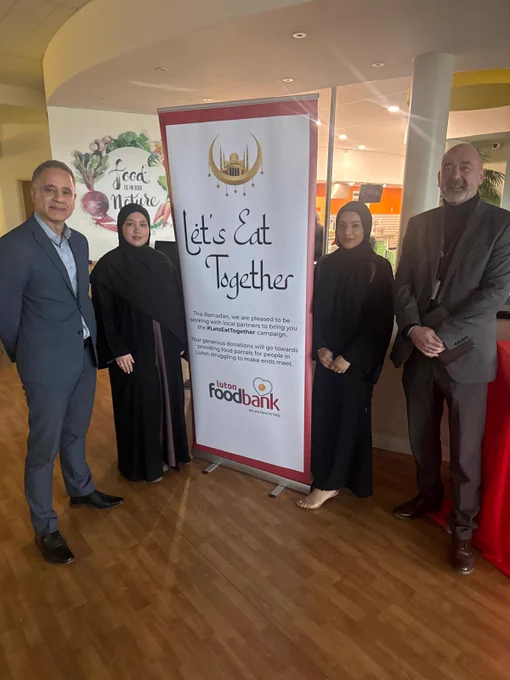 Organisers stand next to a banner reading "Let's Eat Together".
