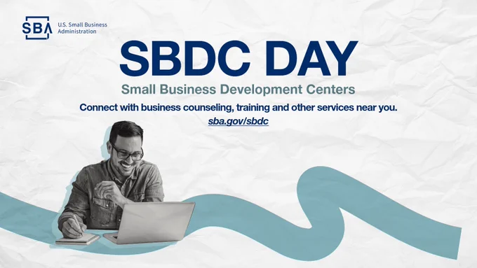 A man is seated at a desk, smiling and reviewing documents. The background displays the U.S. Small Business Administration logo and large text reading "SBDC Day, Small Business Development Centers." A blue wavy line is at the bottom. Additional text reads, "Connect with business counseling, training and other services near you. sba.gov/sbdc."