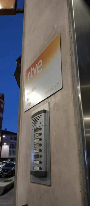Entrada al portal de la unidad informativa de RTVE en Palencia, con el cartel de TVE y RNE encima del portero automático