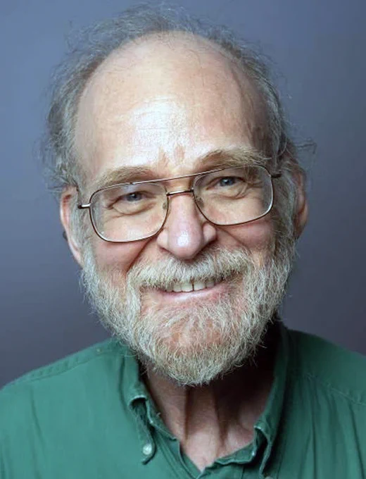 A picture of Joe Halpern smiling in green shirt in front of a blue background.