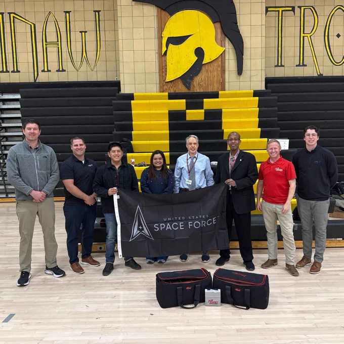 High school teachers standing in gymnasium with United States Space Force flag and a Rocket Drones Classroom Kit.