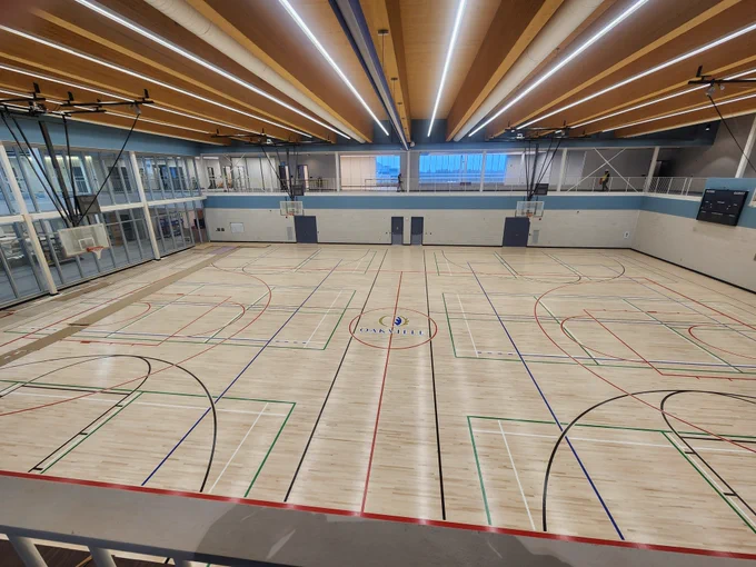 Spacious indoor gymnasium with multiple basketball courts and modern lighting on the ceiling.