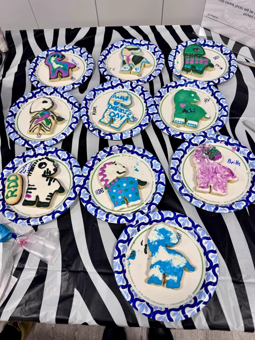 Zebra-shaped cookies with colorful icing on paper plates on a table with a zebra-striped tablecloth