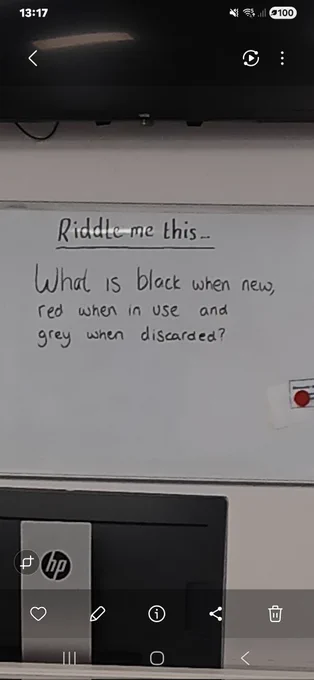 A photo of the wipe board and it says
Riddle me this...
What is black when new, 
red when in use and 
grey when discarded? 