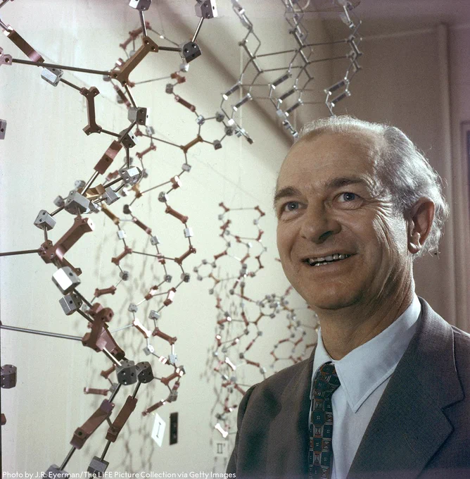 Linus Pauling standing next to a chemical model.