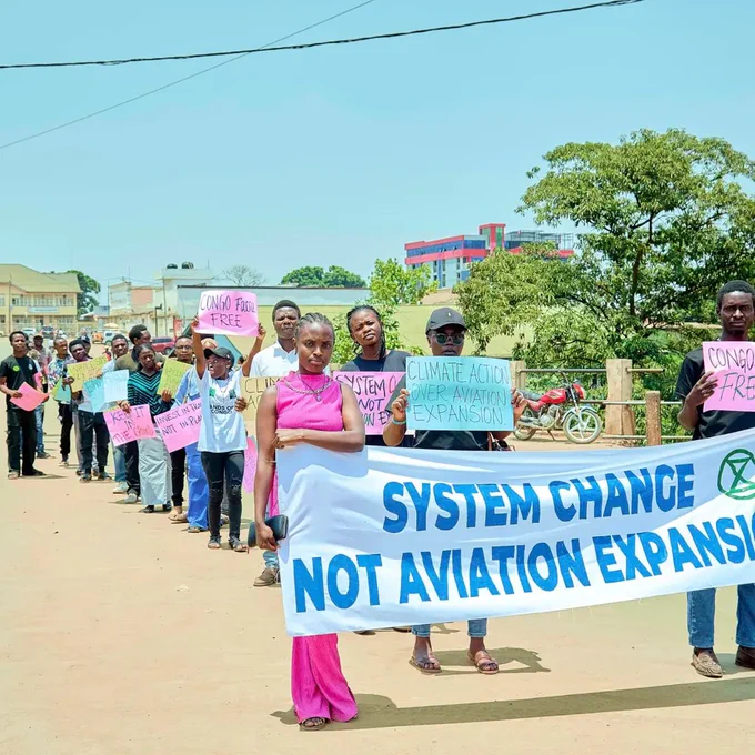 Young people holding banner system change not aviation, as well as several placards against aviation and oil