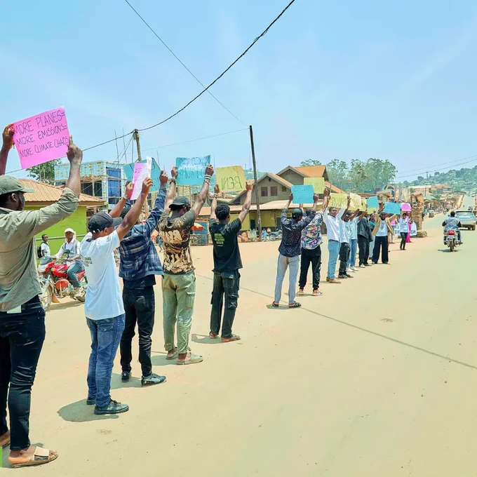 Young people in a line holding  placards against aviation and oil