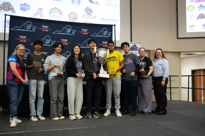 Students from Chantilly Academy stand on stage holding a trophy after winning the Virginia High School Cyber Cup.